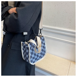 Détail du sac seau en toile à damier avec poignées robustes et bandoulière amovible