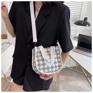 Détail d'un sac bandoulière en toile à motif pied-de-poule gris et blanc avec sangles