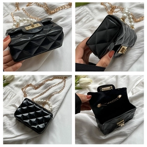 Macro view of black quilted mini bag with pearl handle and golden chain strap details
