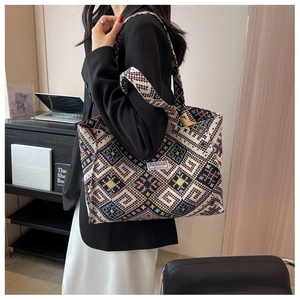 Detailed close-up of a woven tote bag featuring ethnic geometric patterns and fashion label