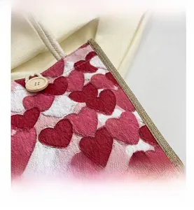 Detail of linen lunch bag showing heart prints, rope handles, and wood button closure