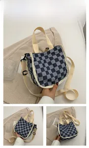 Détail du sac seau en toile à damier montrant la texture du tissu et la bandoulière