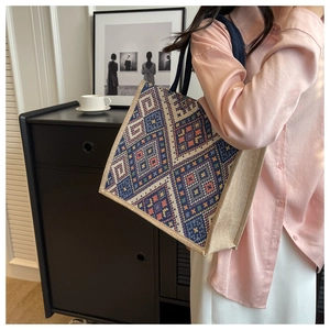 Detail of ethnic geometric woven tote bag with reinforced black shoulder straps on model
