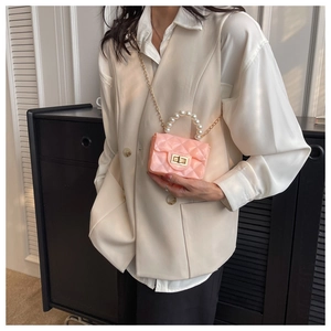 Detail of pink jelly mini bag with pearl handle and quilted pattern worn by a model