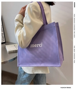 Detail of purple canvas tote bag with white merci print on a stylish female model
