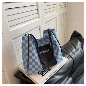 Detailed view of quilted checkerboard tote bag with black leather handles and logo patch