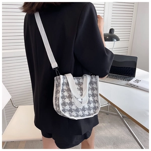 Vue latérale d'un sac bandoulière en toile pied-de-poule avec large sangle sur un mannequin