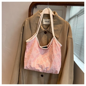 Detail of pink floral tote with embossed texture and slim white shoulder straps