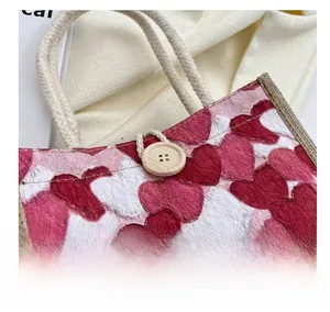 Close-up of wooden button closure and thick rope handles on heart pattern linen tote bag