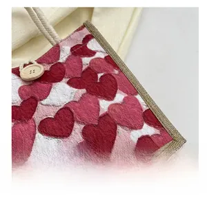 Detail of red heart-patterned canvas bag featuring wooden button and rope handle
