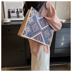 Detailed view of large jute tote bag with ethnic geometric pattern on a model's shoulder