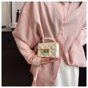 Detail of mini quilted bag with pearl handle and golden metal twist lock closure