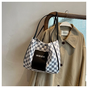 Detail of grey checkerboard tote bag hanging on a trench coat for a stylish look