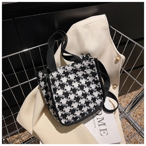 Mini sac chic à motif pied-de-poule noir et blanc posé dans un panier d'achat