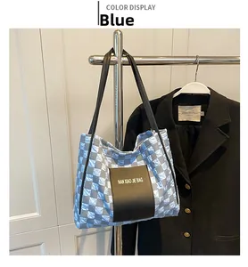 Detail of blue checkerboard quilted tote bag with black leather patch and shoulder strap