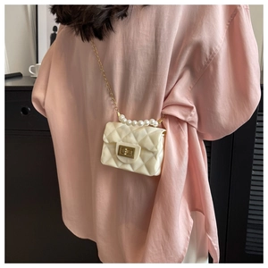 Close-up of a quilted cream mini crossbody bag with pearl handle and gold chain