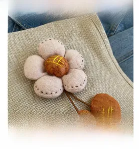 Detail von rosa Strickblume mit gelber Stickerei auf natürlichem Sackleinen-Stoff