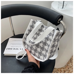 Détail du sac cabas en toile pied-de-poule gris avec poignées tissées sur une chaise
