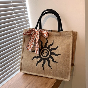 Grand sac cabas en jute rétro avec motif soleil et ruban floral sur un rebord de fenêtre