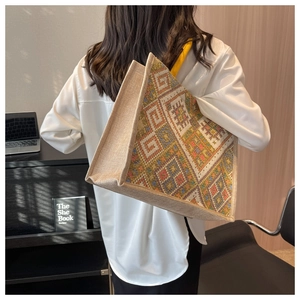 Close-up of geometric woven tote bag with ethnic patterns and yellow canvas handles
