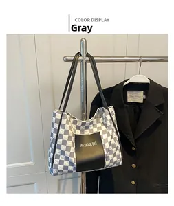 Detail of grey checkerboard tote bag with black shoulder strap and logo patch