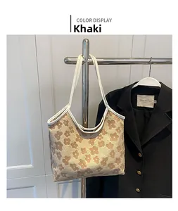 Detail of khaki canvas tote bag featuring white daisy prints and long shoulder handles