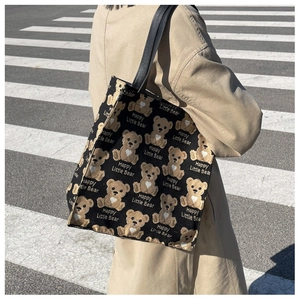 Detail of the black canvas tote bag with leather handles and cute cartoon bear print