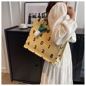 Yellow canvas tote bag with black numbers and a creative green onion plush charm detail