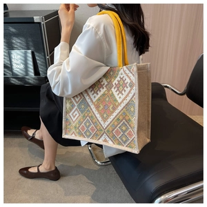 Ethnic style woven tote bag with colorful geometric patterns shown in use on shoulder