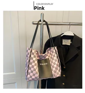 Close-up of pink and grey checkered quilted tote bag with black logo pocket detail