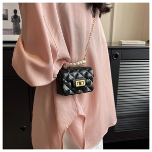 Detail of black quilted mini jelly bag with pearl handle and golden chain strap