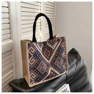 Detail of bohemian woven tote bag with colorful geometric patterns and black handles