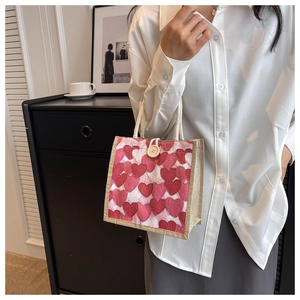 Detail of linen tote bag with red heart pattern and rope handles in a lifestyle setting