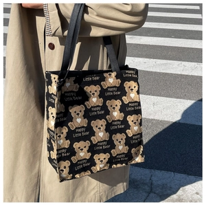 Outdoor lifestyle shot of a black canvas tote bag with a cute cartoon bear pattern