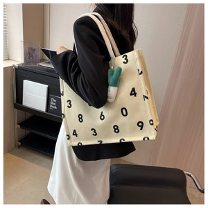 Detail of canvas tote bag with black numeric print and cartoon green onion charm