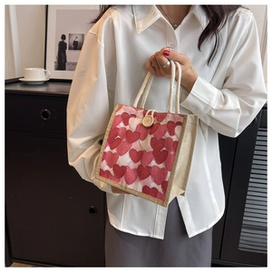 Detail view of woven linen lunch bag with pink heart patterns and wooden button closure