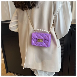 Mini lavender jelly bag with pearl handle and gold chain strap shown on a white shirt
