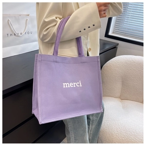 Detail of purple canvas tote bag with white merci print and durable textured fabric