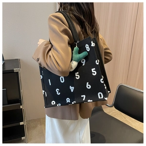 Close-up of black canvas tote bag featuring large white number prints and green cactus charm