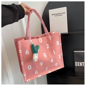 Pink canvas tote bag with white number prints and green plush charm accessory