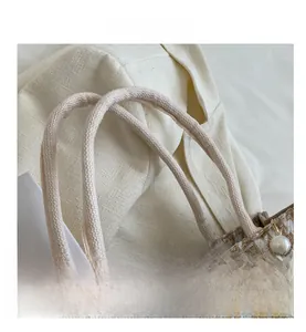 Detail of checkered woven tote with thick rope handles, pearl charms and wooden buttons