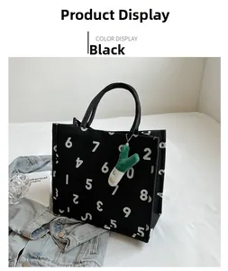 Detail of black canvas tote bag with white number pattern and green vegetable charm