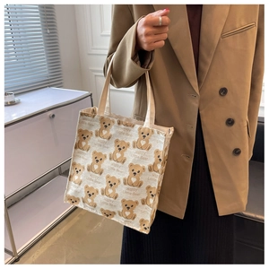 Detail of canvas tote bag featuring cute cartoon bear prints and dual handles