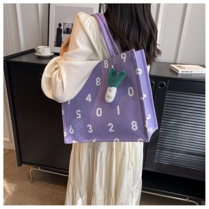 Detail of purple canvas tote bag featuring white number prints and green onion plush charm