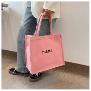 Detail showing high-capacity pink canvas tote bag with black merci print for students