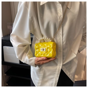 Detail of yellow jelly crossbody bag with quilted pattern and pearl handle shown on model