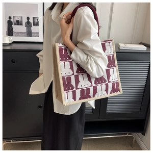 Detail of red checkerboard canvas tote bag with bunny pattern on a shoulder strap