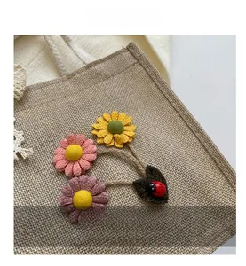 Detail view of woven jute fabric with three 3D fabric daisies and a ladybug ornament