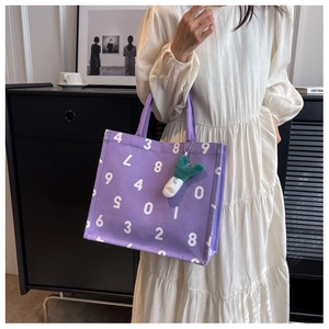 Detailed shot of purple canvas tote bag with white numbers and a green onion plush charm