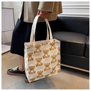 Detailed view of canvas tote bag with Happy Little Bear print held by a model
